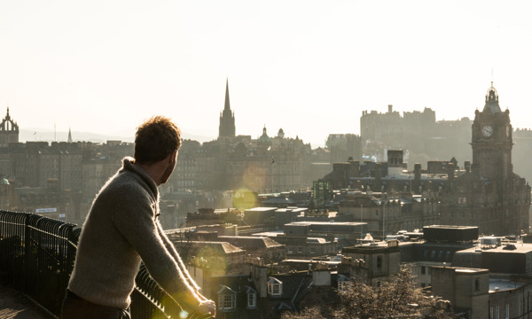 Man admiring the view of Edinburgh from Calton Hill in the sunshine