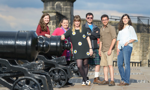 Group of young adults at a castle next to a row of cannons