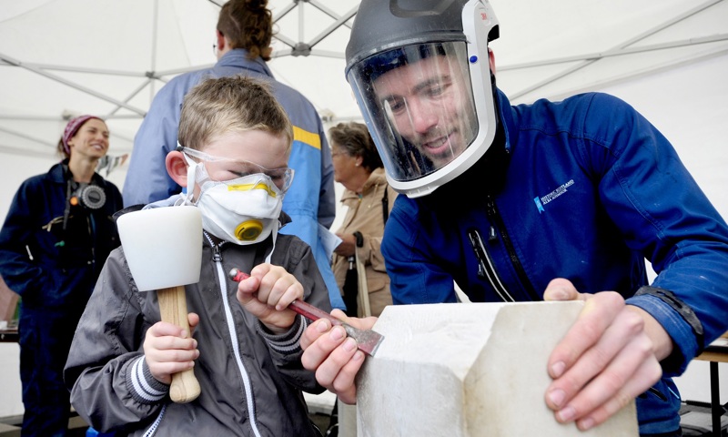 A boy being taught how to excavate using a chisel
