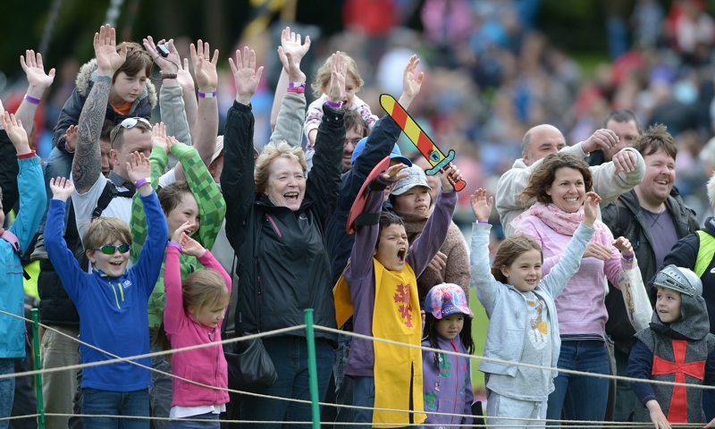 Visitors cheering at Jousting with their arms in the air
