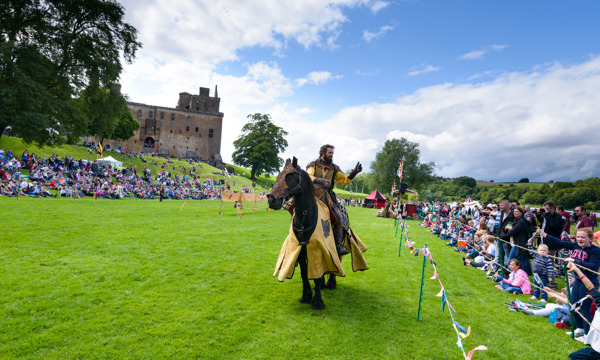 A jouster at Linlithgow Palace rides on horseback past the audience