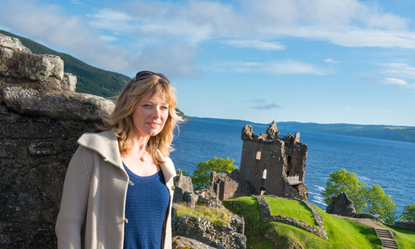 A visitor at Urquhart Castle with the castle and Loch Ness in the background