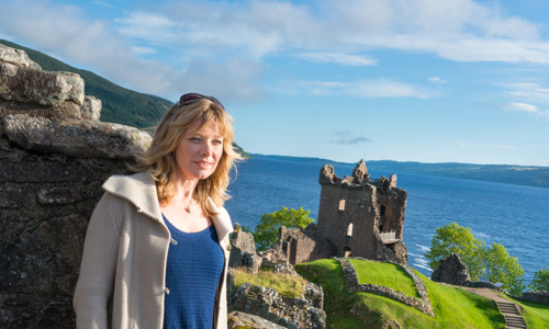A visitor at Urquhart Castle with the castle and Loch Ness in the background