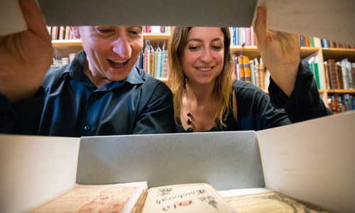 Two people looking inside a box of books, photo taken from inside the box