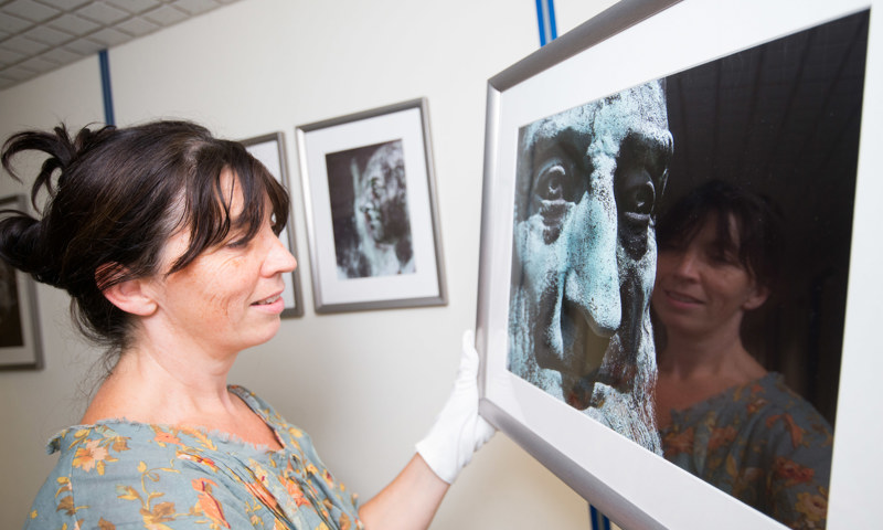A curator in a gallery holding up a picture in a frame
