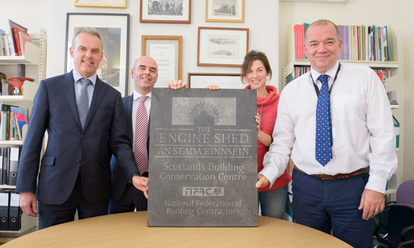 Four people standing next to a plaque for The Engine Shed
