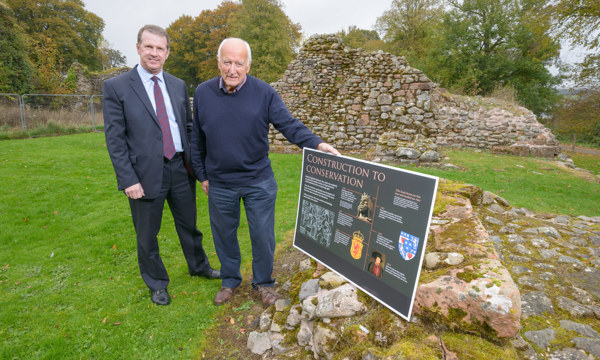 Two men in a park next to a sign headed "Construction to Conservation"