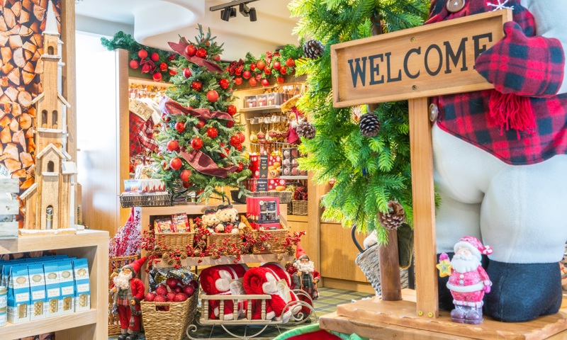 Christmas gift shop with snow man ornament holding a Welcome sign, with a mini santa and a Christmas tree in the background