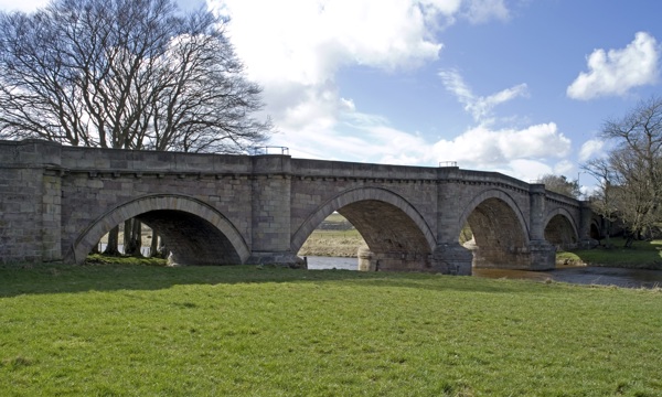 Angled view of Hyndford Bridge from close to its banks with grass in the foreground