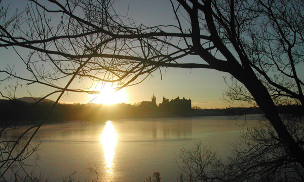 A photograph of a castle silhouetted as the sun sets behind it.