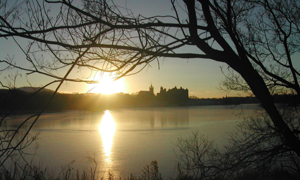 A photograph of a castle silhouetted as the sun sets behind it.