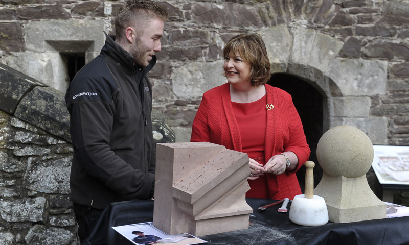 Two people standing behind a table with some stone objects on it