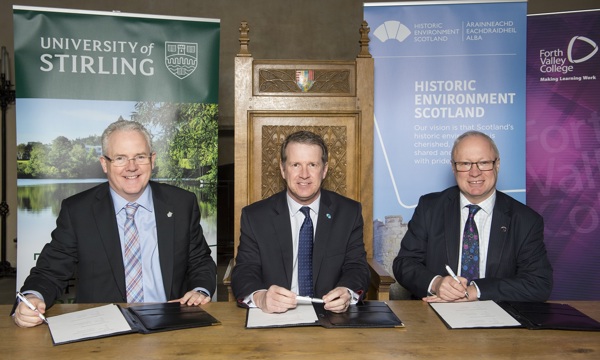 Photo of three signatories of partnership agreement between Stirling University, Historic Environment Scotland, and Forth Valley College, with each of their organisations' vertical banners behind them