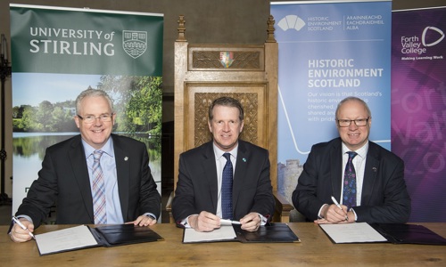 Photo of three signatories of partnership agreement between Stirling University, Historic Environment Scotland, and Forth Valley College, with each of their organisations' vertical banners behind them