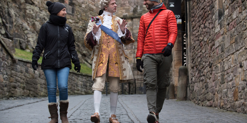 Mark Kydd, dressed as Bonnie Prince Charlie, talking with tourists at Edinburgh Castle