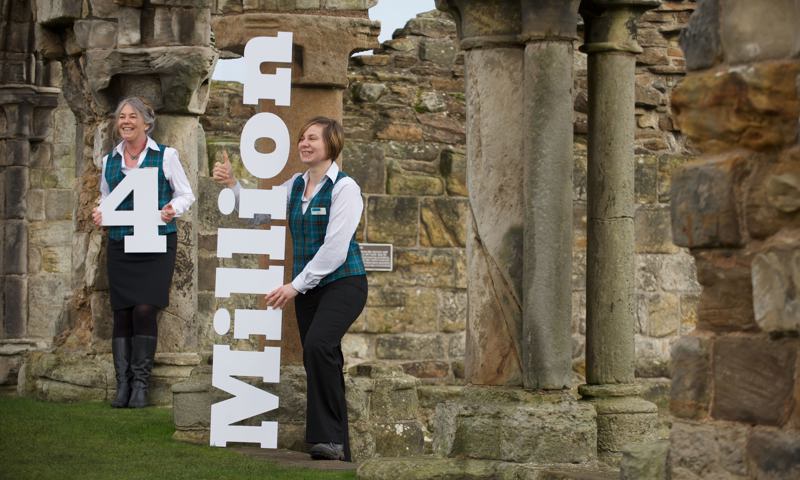 2 members of staff at St Andrews Cathedral holding a large 3D sign that reads "4 Million"