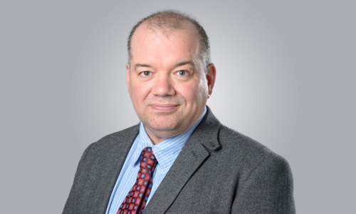 A man wearing a suit and red tie smiling at the camera