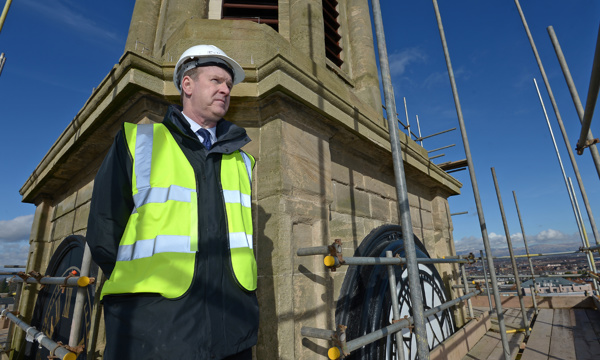 Man in hard hat and high visibility vest on scaffolding at the top of The Falkirk Steeple