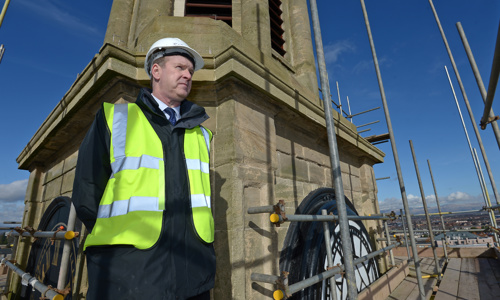 Man in hard hat and high visibility vest on scaffolding at the top of The Falkirk Steeple