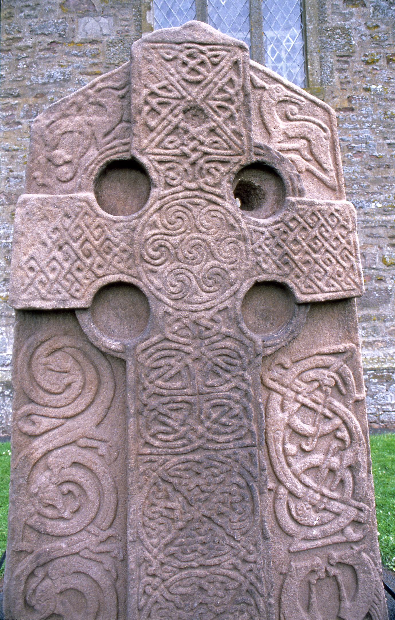 Intricate details and patterns on a carved stone cross. Many resemble celtic crosses and knots.