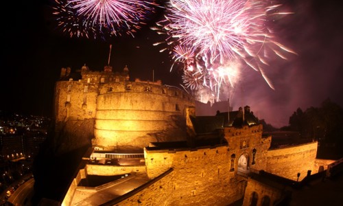 A photograph of a castle at night with fireworks exploding over it
