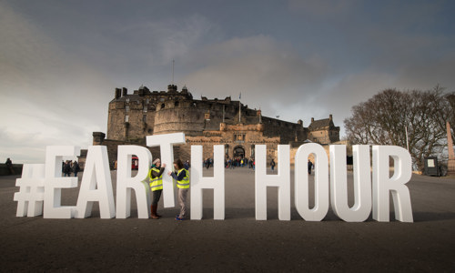 A photograph of a castle with the words #Earth Hour spelled out in front of it