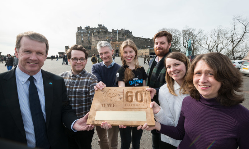 A photograph of seven people holding a wooden award with a panda and WWF on it.