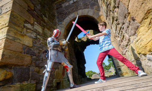A knight and a school child having a dual with swords under an archway