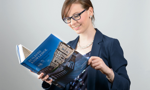 Woman reading a large book entitled "Building Knowledge"