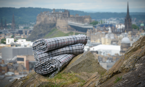 A photograph of a set of tweet blankets on top of some rocks with a castle and city in the distance