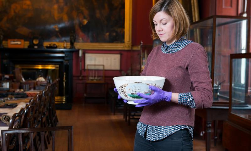 A museum curator holding an ornate bowl