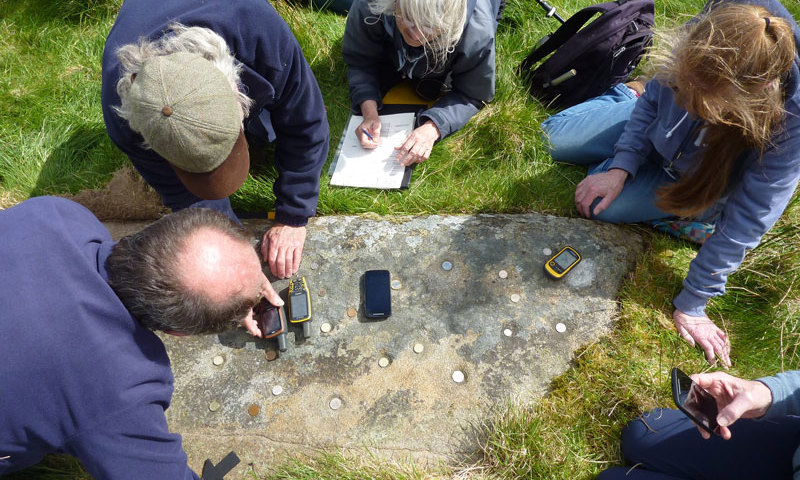Photograph of a group of researchers recording the markings on a rock face