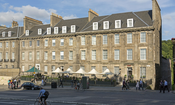 4 story row of tenements with umbrellas at street level in front of them