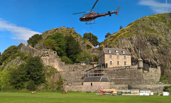 chopper flies over historic castle on a rocky outcrop