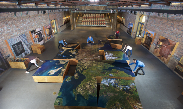People assembling segments of a large map of Scotland at The Engine Shed