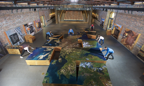 People assembling segments of a large map of Scotland at The Engine Shed