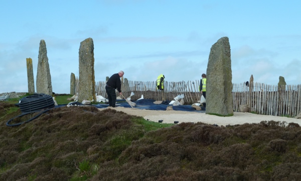 5 standing stones with workers laying new path beside them