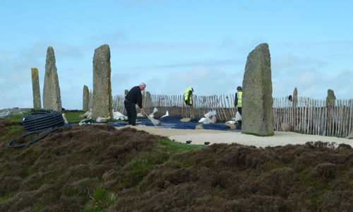 5 standing stones with workers laying new path beside them