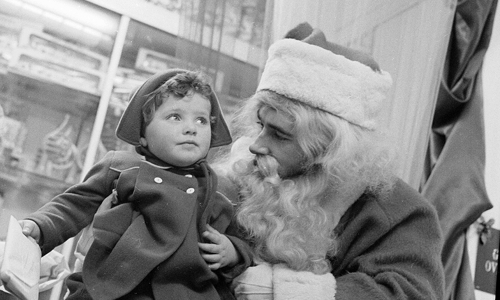 black and white image of a small child sitting on santa's knee