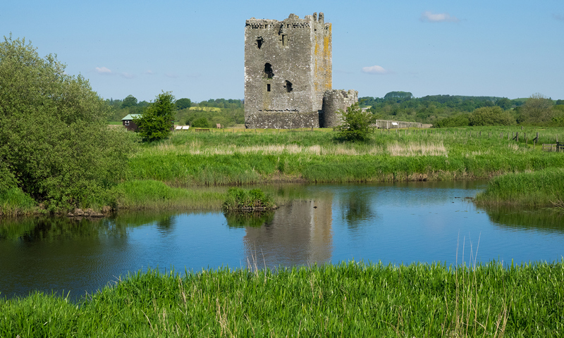 expanse of water with tower building on an outcrop in the middle and blue sky above