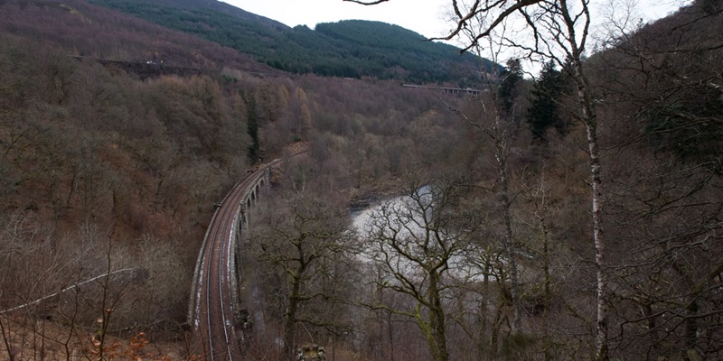 A photograph of a landscape with a railway bridge running through it.