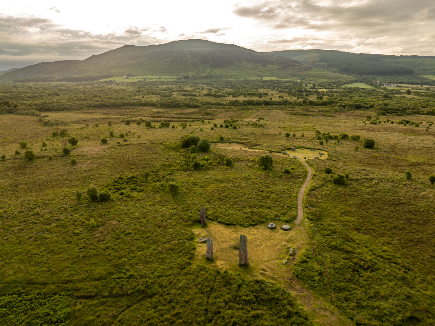 Aerial view of three standing stones, in a rural landscape. 