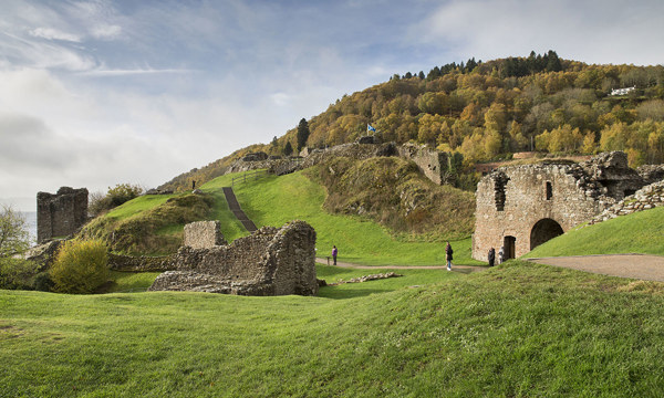 ruined building in front of a green hill covered in trees