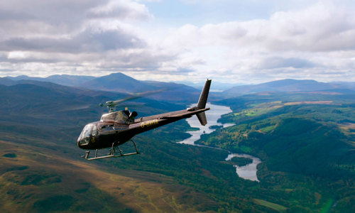 A photograph of a helicopter over hills.