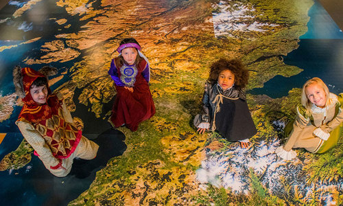 Image of four children dressed in medieval clothing sitting on 3D map of Scotland
