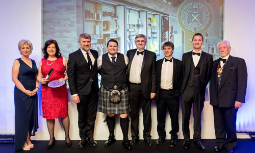 Members of the Engine Shed team and Engine Shed architects and creators stand together smiling whilst holding up a RIAS Award for the Best Building