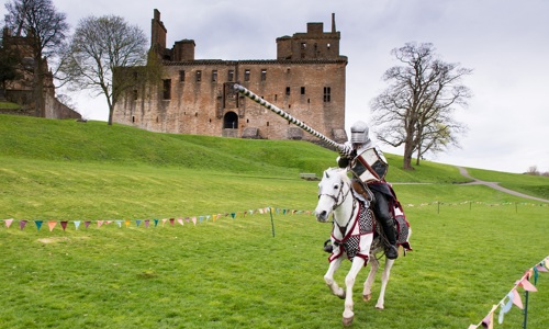 a knight on horseback gallops at the camera with a lance