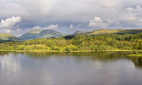 A big lake and hills in the distance on a cloudy day.