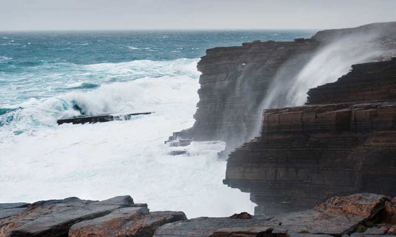 Sea waves breaking against steep cliffs.