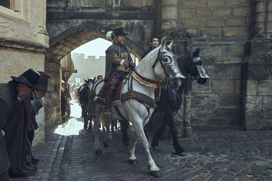 Two actors dressed in period costume on horses coming through the portcullis at Stirling Castle 